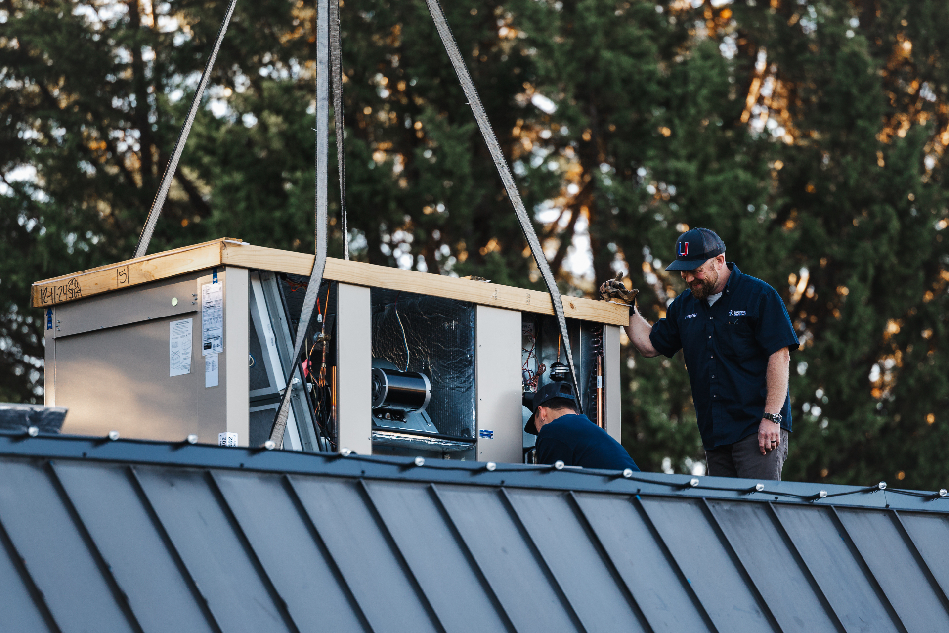 Uptown Air Conditioning mechanics installing a commercial rooftop HVAC unit